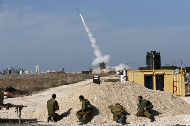 Israeli-soldiers-watch-as-an-Iron-Dome-launcher-fires-an-interceptor-rocket-near